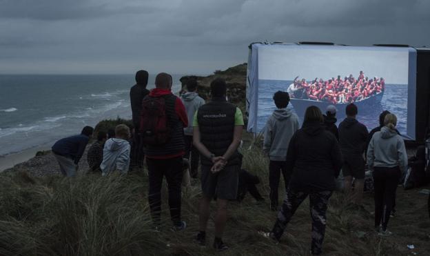 En gruppe efterskoleelever ser Jacob Ehrbahns billeder af flygtninge i Middelhavet projekteret op på PixlArt-bussen. <i>Pixlart</i>