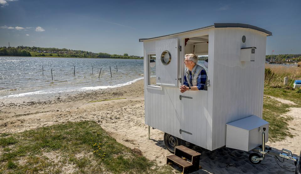 Hans Pedersens drøm om et badehus er gået i opfyldelse. Her nyder han udsigten over Mariager Fjord, men han kan køre lige, hvorhen han vil med sit lille hus, for teknisk set er der blot tale om en trailer. Se hvordan den fingersnilde pensionist byggede det fine hvide hus på hjul. <i>Foto: Lars Pauli</i>