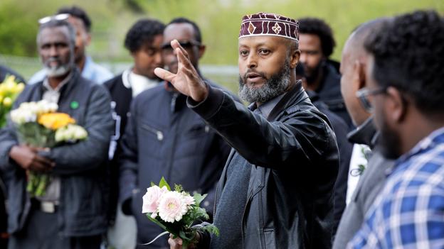 Imam Mustafa Aden talte for forsamlingen, inden blomsterne blev lagt ved hegnet. <i>Foto: Henrik Bo</i>