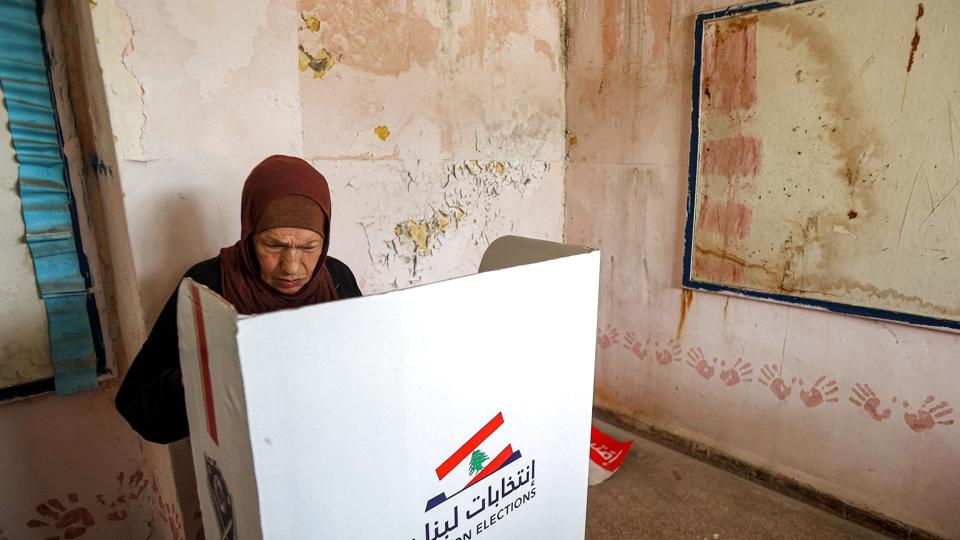 En kvinde afgiver sin stemme ved valget søndag. Hizbollah og gruppens allierede får 62 af de 128 pladser i parlamentet. Forud for valget sad de på 71 af pladserne og havde dermed flertal. Resultatet betegnes som et kæmpe tilbageslag for den tungt bevæbnede milits. <i>Anwar Amro/Ritzau Scanpix</i>