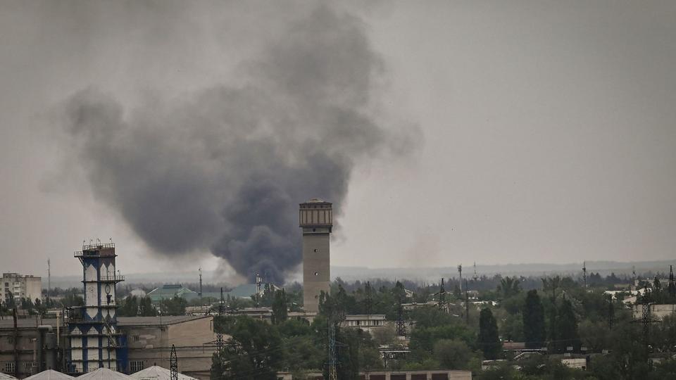 Røg ses stige op mellem Sjevjerodonetsks tage, efter at byen lørdag blev ramt af russisk granatild. <i>Aris Messinis/Ritzau Scanpix</i>