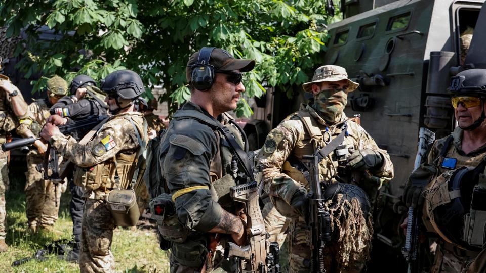 Soldater fra en deling af udenlandske frivillige, der kæmper for den ukrainske hær, ses her ved et militærkøretøj i Sjevjerodonetsk torsdag, mens Ruslands forsøg på at indtage Ukraine fortsætter. <i>Serhii Nuzhnenko/Reuters</i>