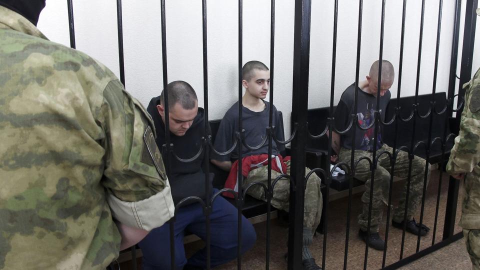 I et område af Donetsk i Ukraine, som er under russisk beskyttelse, blev to briter torsdag dømt til døden for at have kæmpet til fordel for Ukraine. Imellem dem sidder en ung marokkaner. De blev alle tre dømt til døden. <i>Uncredited/Ritzau Scanpix</i>
