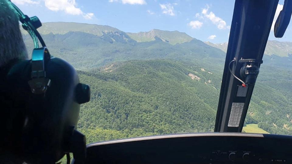 En redningshelikopter flyver lørdag hen over det sted ved Pievepelago i Italien, hvor syv mennesker er blevet dræbt i et helikopterstyrt. <i>Corpo Nazionale Soccorso Alpino/Reuters</i>
