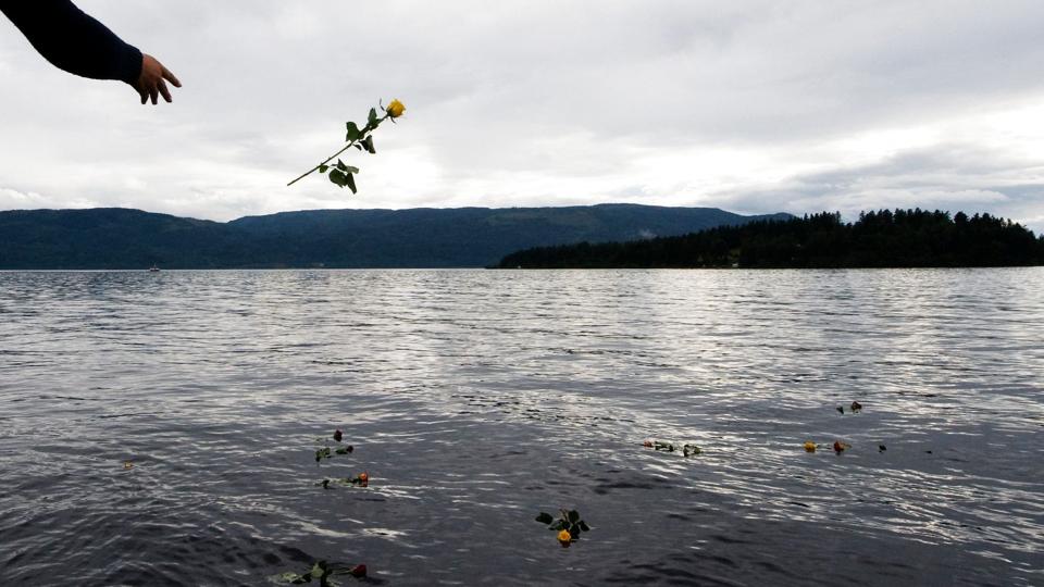 Arkivfoto fra 2011 viser kvinde, som kaster en rose i vandet nær Utøya for at mindes ofrene for angrebet den 22. juli.  Norge indviede lørdag et nyt nationalt mindemonument på Utøya for ofrene for angrebet i 2011. Mindesmærket er bygget ved kajen på fastlandet ud mod øen Utøya. <i>Jonathan Nackstrand/Ritzau Scanpix</i>