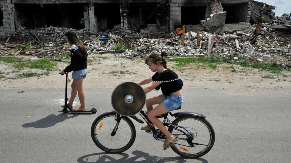 To børn cykler forbi en ruin af en bygning i Tjernihiv-regionen, der flere gange er blevet ramt af russiske angreb. Lørdag melder Ukraines hær om kraftig beskydning fra hviderussisk territorium. <i>Sergei Chuzavkov/Ritzau Scanpix</i>