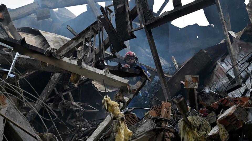 En ukrainsk brandmand arbejder i ruinerne af den beboelsesejendom i hovedstaden Kyiv, der søndag er blevet ramt under et russisk angreb. Også en børnehave skal være ramt. <i>Sergei Supinsky/Ritzau Scanpix</i>