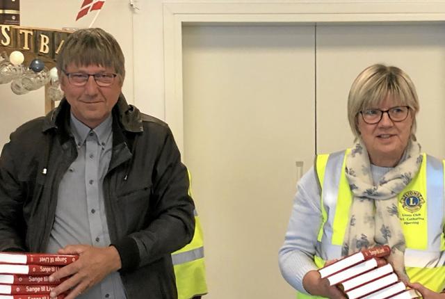 Niels Erik Simonsen og Helle Nørkjær fra Lions i gang med at uddele sangbøger. Foto: Susanne Thomsen