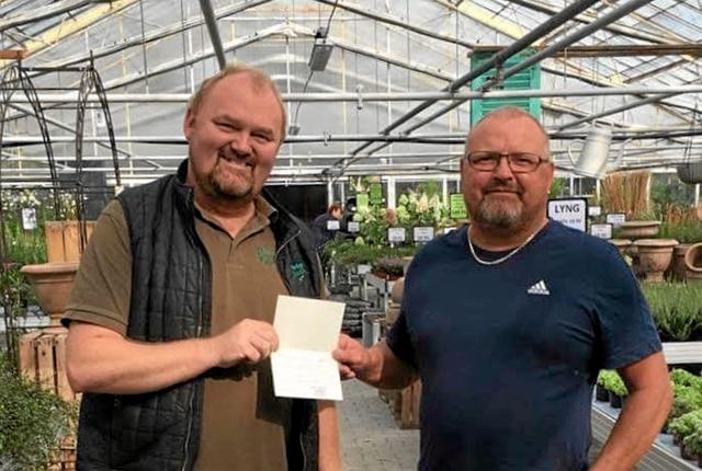 Lasse Pedersen fra Sæby Planteskole overrækker det velfortjente gavekort på 1.000 kroner til vinderen, Mogens Ørum. Foto: Privat