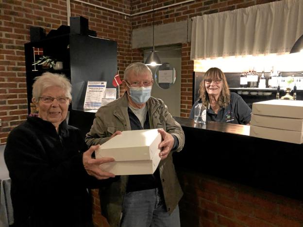 Næstformand Helmer Nielsen overrækker to æsker smørrebrød til Ingrid Andresen fra Vrensted, og bag disken står Janjette Træholt fra Restaurant Strandgården klar med flere æsker. Foto: Kirsten Olsen