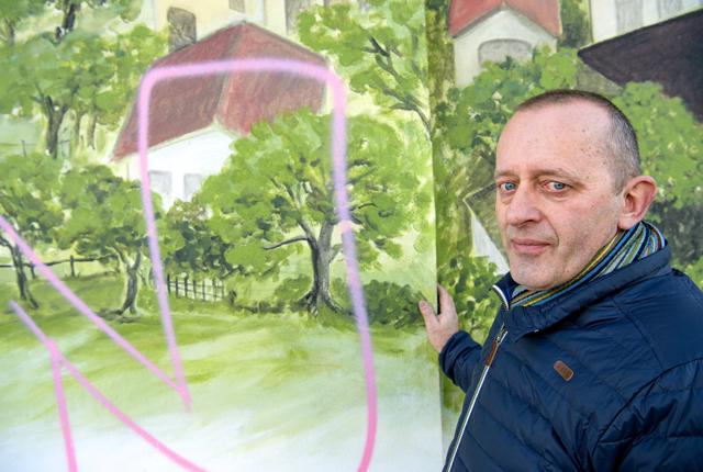 Jens Christian Nielsen ærgrer sig over, at byens fine maleri er blevet udsat for hærværk i form af graffiti.