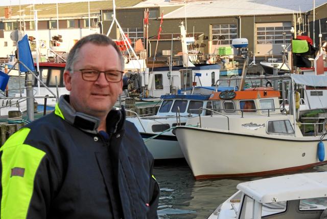 Fritidsfisker Jens Holm foran jollehavnen, og foran sin egen båd Sneglen med det orange tag, som han ofte tager ud i når vejret og tiden tillader det. Foto: Jens Brændgaard