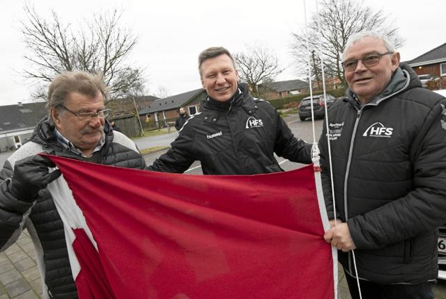 Flaget blev sendt til tops af de to æremedlemmer Preben Thomsen (t.v.) og Niels Gunnar Nielsen (t.h.). De to flankerer her træner Anders Langeland. Foto: Allan Mortensen