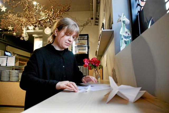 Emilie Jensen, som er værtinde på Museum for Papirkunst, viser, hvordan et papirfly kan foldes. Foto: Bitten Holmsgaard