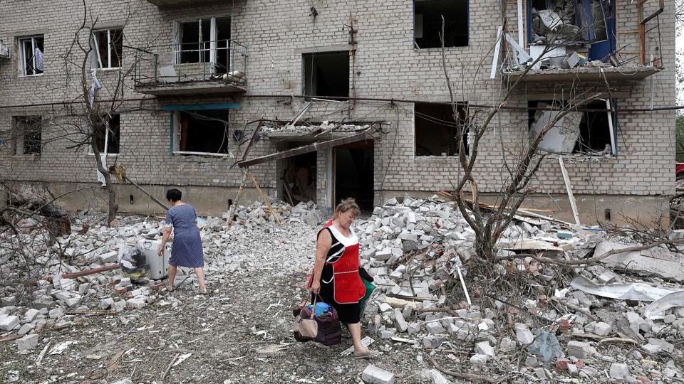 En kvinde bærer sine ejendele ud af den bygning i Tjasiv Jar, der lørdag blev ramt af et missilangreb. <i>Anatolii Stepanov/Ritzau Scanpix</i>