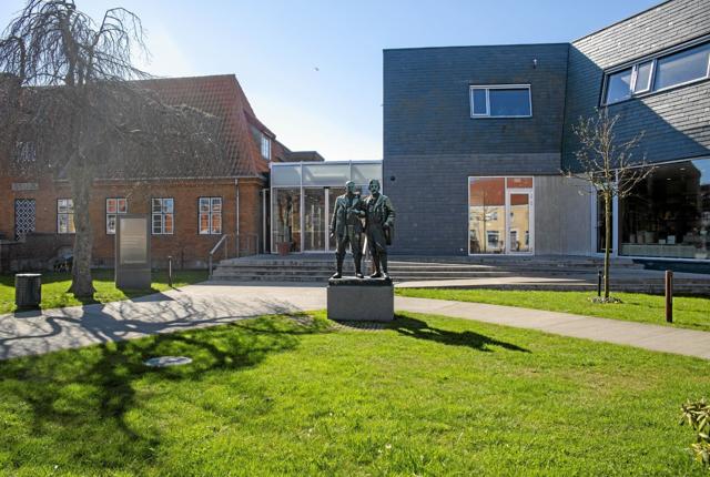 Påskens oplevelser på Skagens Museum begynder her. Til højre for Laurits Tuxens dobbeltstatue af P.S. Krøyer og Michael Ancher udstilles hver dag tre nye malerier i konserveringsværkstedets store vinduer, og gåturen i skagensmalernes kvarter begynder foran selv samme statue. Foto: Skagens Kunstmuseer