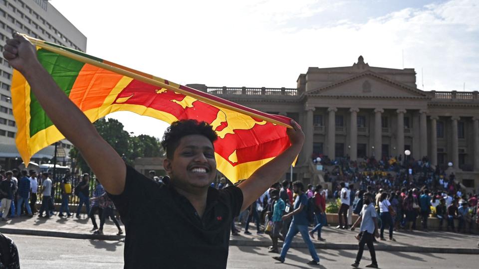 En demonstrant med Sri Lankas nationale flag uden for præsidentboligen i Colombo, hvor uroligheder fortsætter. Der er onsdag blevet indført landsomfattende nødretstilstand i hele Sri Lanka, efter at præsident Gotabaya Rajapaksa er flygtet fra østaten. <i>Arun Sankar/Ritzau Scanpix</i>