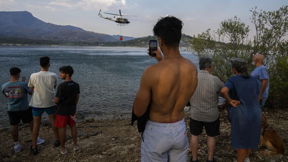 En helikopter forsøger at slukke en naturbrand ved et vandreservoir nær Madrid. Vesteuropa døjer med endnu en hedebølge inden for kort tid. Varmen forværrer naturbrande mange steder. Tusindvis af mennesker blev evakueret ved den franske Atlanterhavskyst onsdag. <i>Bernat Armangue/Ritzau Scanpix</i>