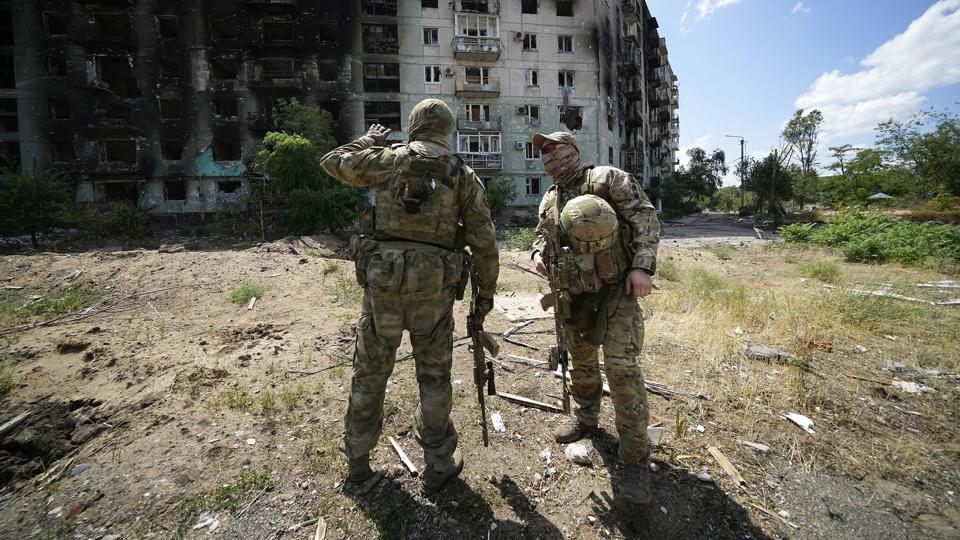Den russiske hær er angiveligt i bekneb for kampklare soldater til at indgå i krigen i Ukraine. Her ses to russiske soldater ved en boligblok, der er beskadiget under kampe mellem russiske og ukrainske styrker i Luhansk-regionen i det østlige Ukraine. <i>Uncredited/Ritzau Scanpix</i>