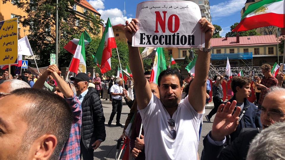 Iraneren Hamid Noury blev torsdag i sidste uge dømt for at have deltaget i massehenrettelser af hundredvis af politiske fanger i Iran i 1988 i et fængsel nær Teheran. Her ses demonstranter ude foran domstolen i Stockholm. <i>Staff/Reuters</i>