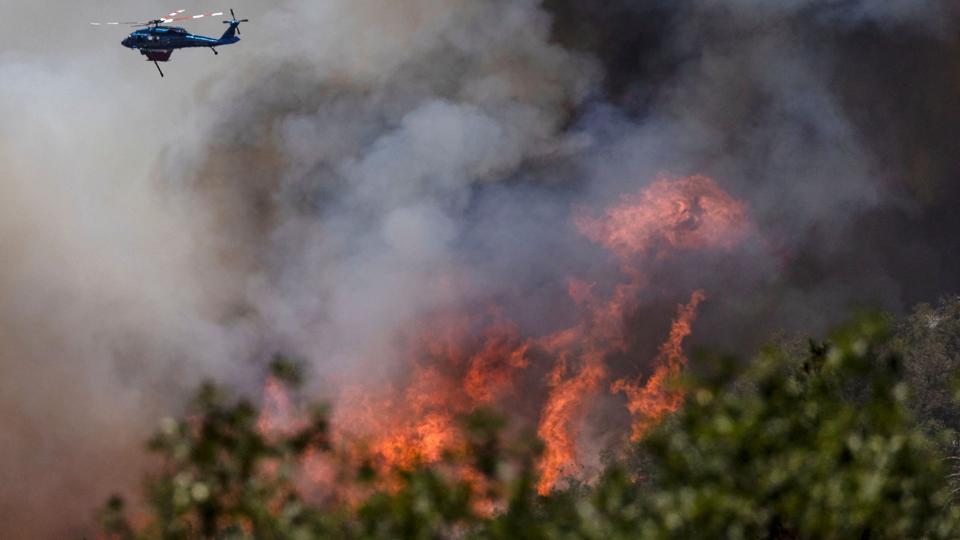 En helikopter smider vand på den enorme skovbrand Oak Fire, som i øjeblikket raserer i det centrale Californien. <i>Carlos Barria/Reuters</i>