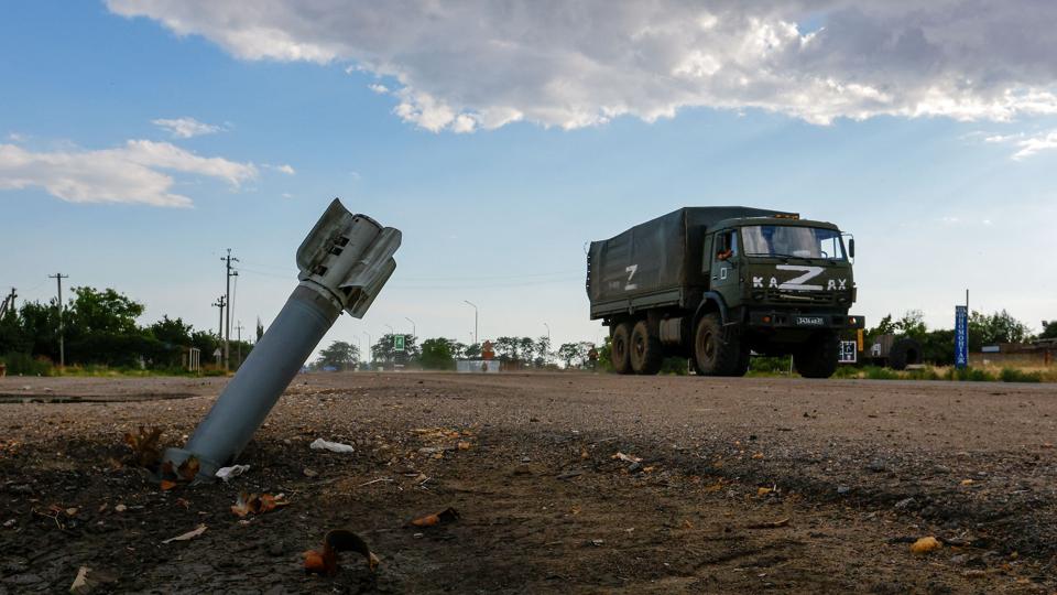 En lastbil fra det russiske militær kører forbi en ueksploderet granat i en russiskkontrolleret landsby i det sydlige Ukraine. <i>Alexander Ermochenko/Reuters</i>