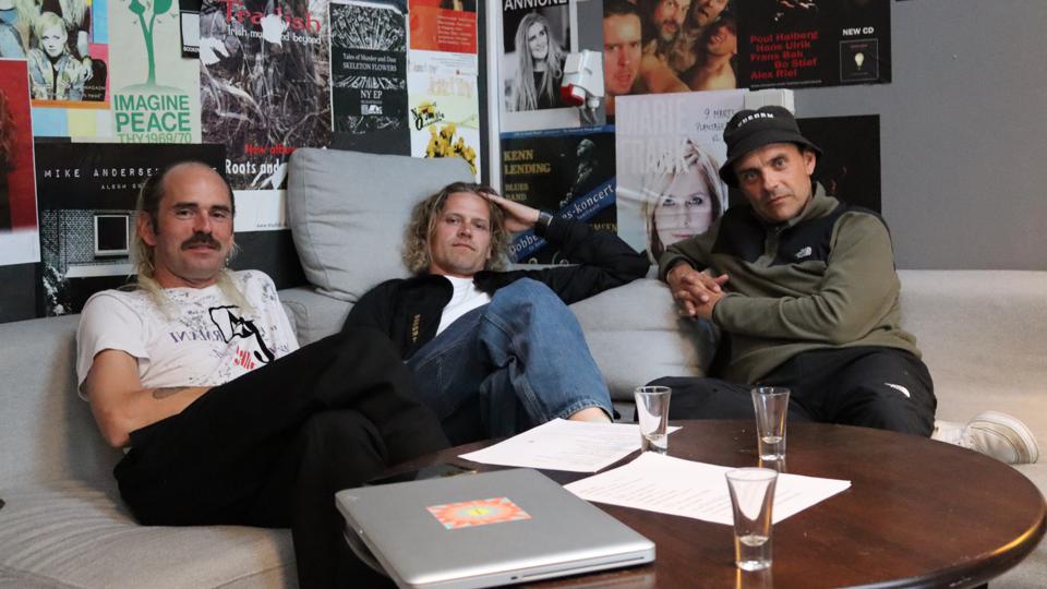 HUGORM er både spændte og nervøse, men på den gode måde, inden deres koncert til Alive Festival. Om det er for at dulme nerverne vides ikke, men de tre medlemmer havde i hvert fald tømt shots-glassene foran dem. <i>Foto: Mads Kappel Thøgersen</i>