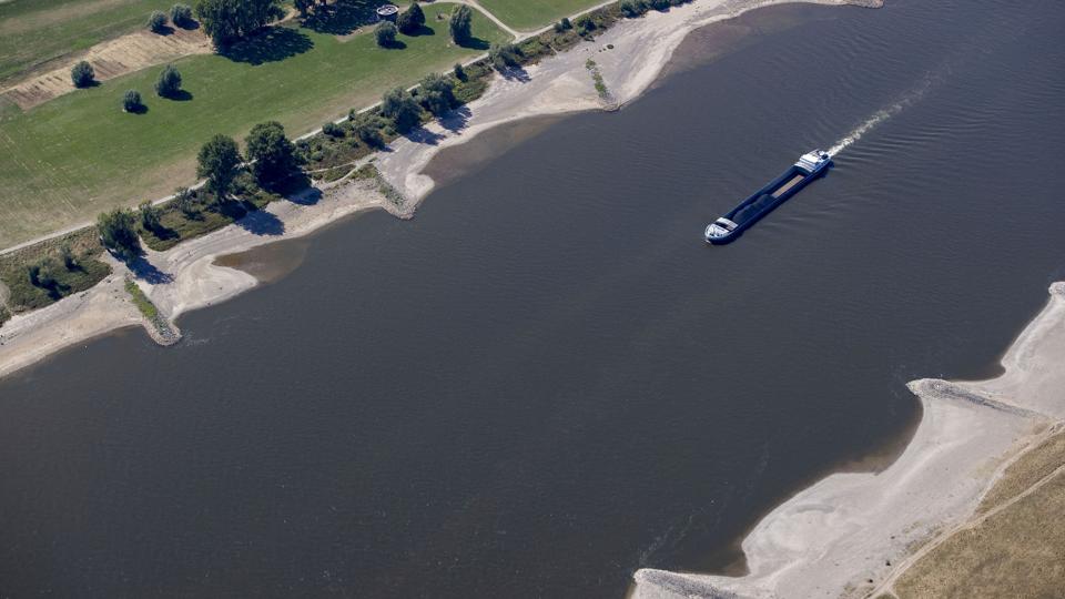 Et skib uden ret megen last bevæger sig frem på Rhinen mellem Köln og Düsseldorf. Skibstrafikken er alvorlig ramt af tørken og den lave vandstand i floden, der er en Tysklands vigtigste handelsruter. <i>Christoph Reichwein/Ritzau Scanpix</i>