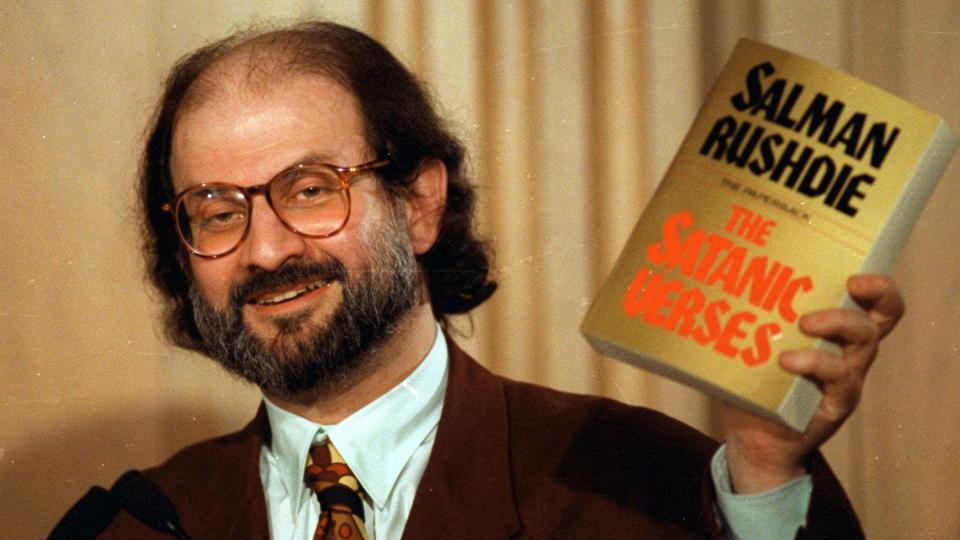 Salman Rushdies bog "De sataniske vers" udløste kort efter udgivelsen i 1988 demonstrationer verden over. Efter et angreb på Rushdie fredag er den skudt helt op i toppen af Saxos bestsellerliste. Billedet viser den i dag 75-årige forfatter fotograferet med sin kontroversielle bog i 1992. <i>Ron Edmonds/Ritzau Scanpix</i>