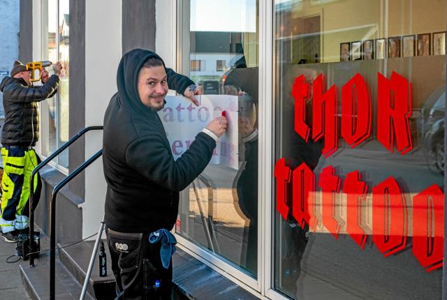 Anders Thomsen og Adam Szalai fjerne gamle skilte fra vinduerne og sætter det nye logo op. Foto: Niels Helver