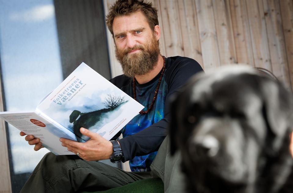 Mads Martedahl Knudsen med bogen om "Folketroens væsner", som han har udgivet på sit nye forlag,  Ættaborg. Til højre familiens hund, Ulf. <i>Foto: Bo Lehm</i>