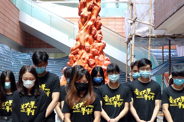 Universitetsstuderende i et øjebliks stilhed foran Jens Galschiøts skulptur 'Skammens søjle', opført til minde for ofre under protesterne på Tiananmen-pladsen i Beijing i 1989. I december sidste år fjernede universitetet skulpturen, der har stået på campus siden 1997, i forbindelse med en ny sikkerhedslov fra Kina, der siger, at man ikke må kritisere regeringen. <i>Foto: Jessie Pang/Reuters/Ritzau Scanpix</i>