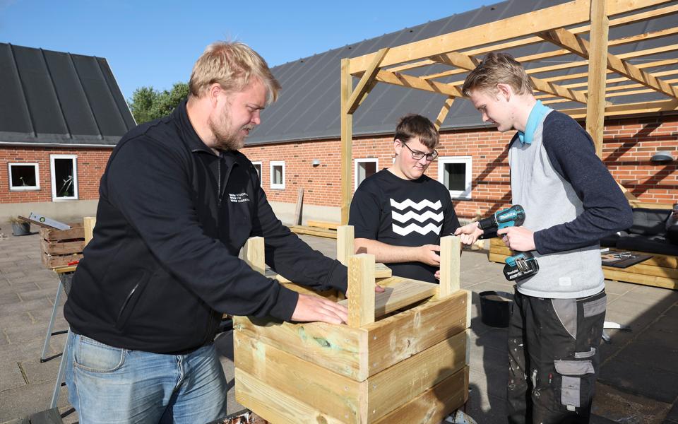 Faglærer Tobias Steen Jensen sammen med eleverne Janus Bergmann Kellin og Oliver Lund - her er de i gang med at lave en blomsterkasse. <i>Foto: Bente Poder</i>