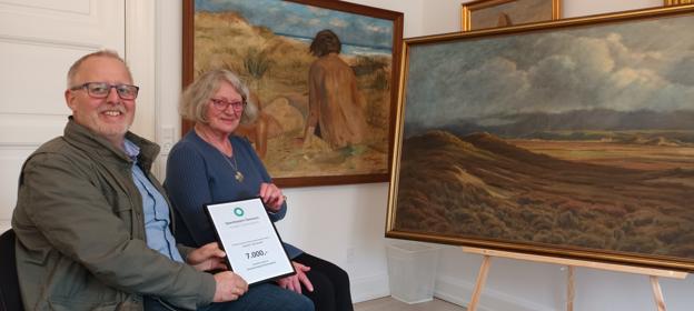 Afdelingsdirektør Henrik Jensen fra Sparekassen Danmark i Fjerritslev overrækker beviset for sponsoratet på 7.000 kroner til Herdis Lau. Nielsen, der er formand for projekt Kunsten i Han Herred. Pengene går til den vellykkede restaurering af de to viste værker af henholdsvis Martin Konopacki og Ingvor Groth. <i>Ejgil Bodilsen</i>