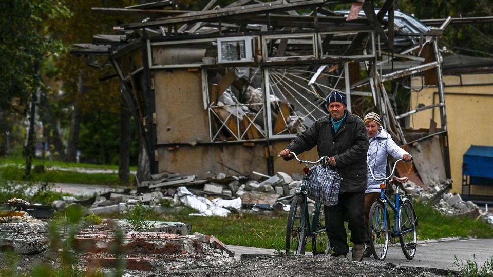 Et par trækker deres cykler gennem en udbombet del af byen Izium, som Ukraines præsident, Volodymyr Zelenskyj, søndag aften bekræfter er blevet generobret fra Rusland. <i>Juan Barreto/Ritzau Scanpix</i>