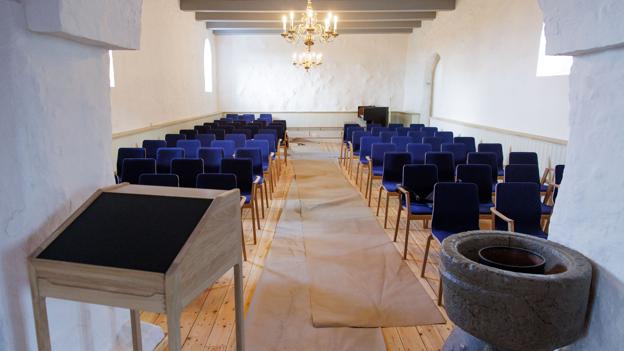 Den gamle prædikestol er taget ned og afløst af en talerpult, den romanske døbefond hugget i granit understreger kirkens århundrede gamle historie, men nu står den i et rum, hvor kirkebænkene er skiftet ud med moderne stole som hurtigt kan stilles op på nye måder alt efter hvilket formål, rummet skal indgå i. <i>Foto: Bo Lehm</i>