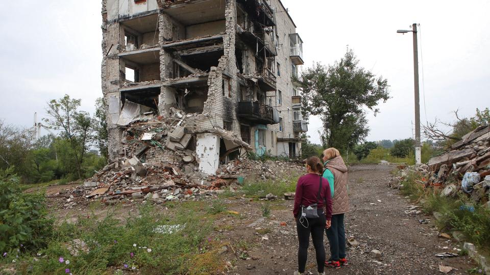 Kvinder ved en udbombet boligblok i byen Izium, som for nylig er blevet befriet af de ukrainske styrker. Der er fundet en massegrav i byen efter den russiske besættelse, siger den ukrainske præsident ifølge nyhedsbureauet Reuters. <i>Stringer/Reuters</i>