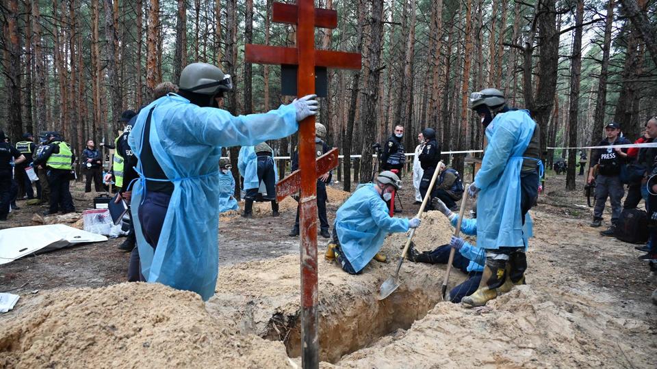 Teknikere arbejder i en skov i udkanten af Izjum fredag. Samme dag siger ukrainske myndigheder, at der er fundet 450 grave ved bare en gravplads i byen. <i>Sergey Bobok/Ritzau Scanpix</i>