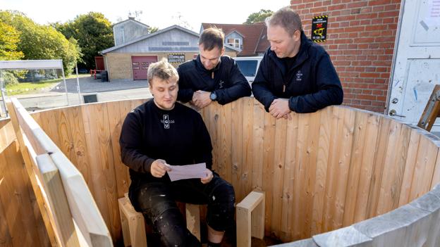 Oliver er den kun anden tømrer, som FGU Himmerland i Hobro har uddannet. Her ses han i et vildmarkskar, han har været med til at bygge, omgivet af faglærerne Lars Norup og Jakob Skov Andersen (yderst t.h.) <i>Foto: Lars Pauli</i>