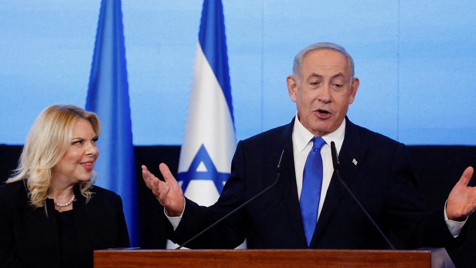 Nu er det officielt. Benjamin Netanyahu og hans allierede har sikret sig flertalte ved valget i Israel. Her under en tale i sit parti Likuds hovedkvarter. Han er flankeret af sine kone Sara. <i>Ammar Awad/Reuters</i>