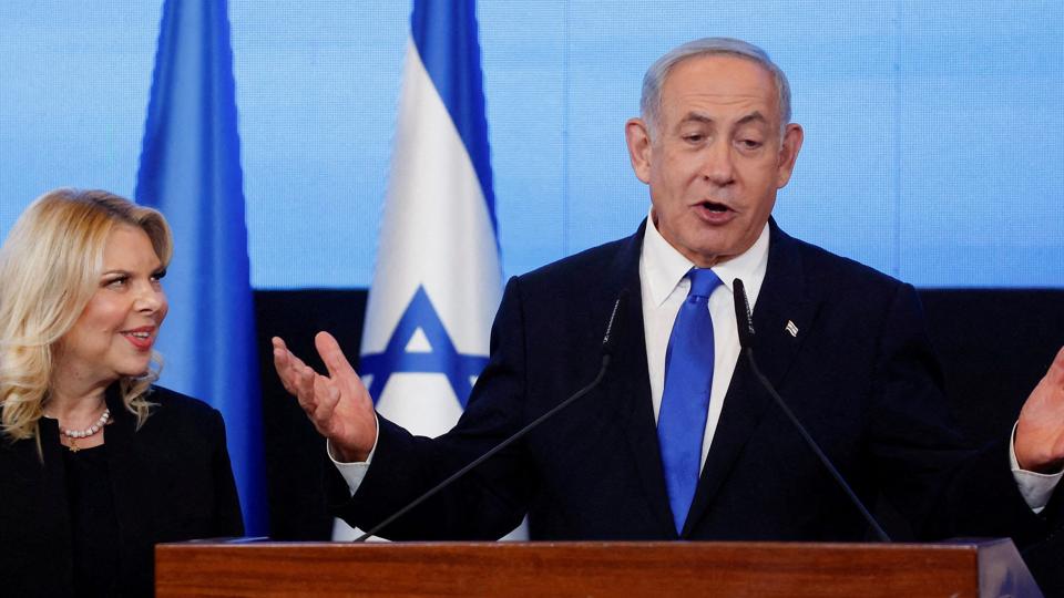 Nu er det officielt. Benjamin Netanyahu og hans allierede har sikret sig flertallet ved valget i Israel. Her under en tale i sit parti Likuds hovedkvarter. Han er flankeret af sine kone Sara. <i>Ammar Awad/Reuters</i>