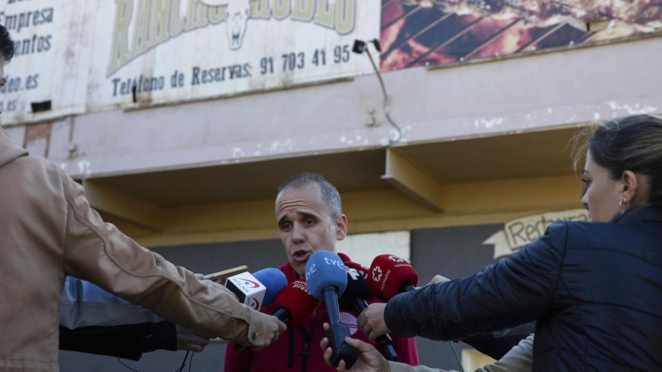 En talsmand for redningstjenesten, David Garcia, taler med spanske medier udenfor restaurant El Rancho i byen Torrejón de Ardoz, der ligger nær den spanske hovedstad, Madrid. Klokken 02.44 natten til søndag kørte en bil ind i en gruppe bryllupsgæster, der stod udenfor restauranten. Forud for det havde der været slagsmål ved brylluppet. <i>Jesús Hellín/Ritzau Scanpix</i>