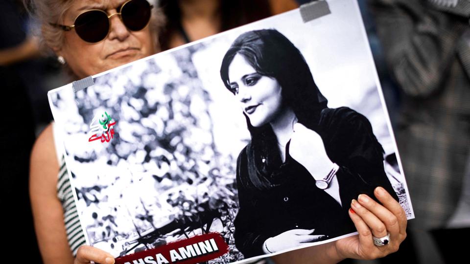 Den 22-årige kurdisk-iranske Mahsa Aminis død i iransk politis varetægt i september udløste store demonstrationer i Iran. Det udgør den største udfordring for præstestyret siden revolutionen i 1979. Her holder en kvinde et billede af Mahsa Amini under en tidligere sympatidemonstration i Paris. <i>Behrouz Mehri/Ritzau Scanpix</i>