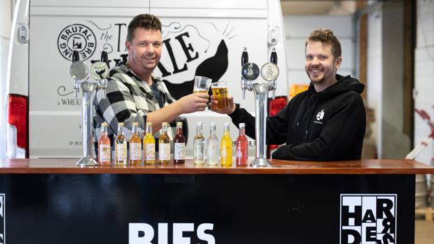 Bies Bryghus betyder meget for Real Drinks. Her har Jens og Christian Dilling taget plads i en mobil bar, som åbenlyst er en god reklame for det gamle bryghus i Hobro. I hanerne eksport øl fra Bie og på bardisken flasker med saft og sodvand fra Bie. <i>Foto: Claus Søndberg</i>