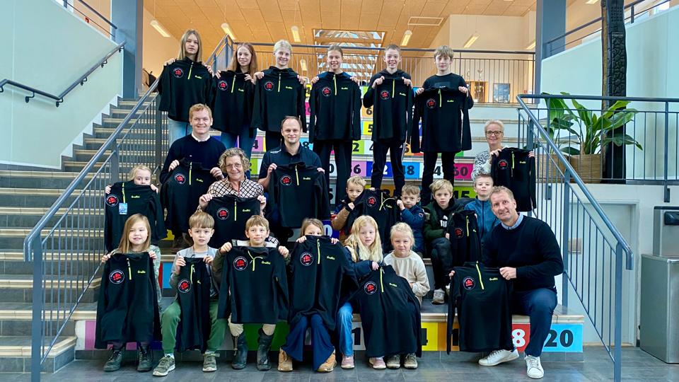 De nye fleecetrøjer skabte glæde hos eleverne fra 1.B, 6.A og 6.B. Med på billedet er Jonas Foged Holm, Feriepartner Thy (tv.), Johnny Andersen, Sportigan Thisted og Hurup og lærerne Malene Larsen og Lotte Vils. Forrest til højre ses skoleleder Per Olesen. <i>Foto: Carsten Hougaard</i>