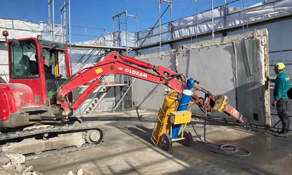 På toppen af højhuset frigøres hvert betonelement og klargøres til at blive hejst ned i de tykke kæder. På toppen af højhuset frigøres hvert betonelement og klargøres til at blive hejst ned i de tykke kæder.