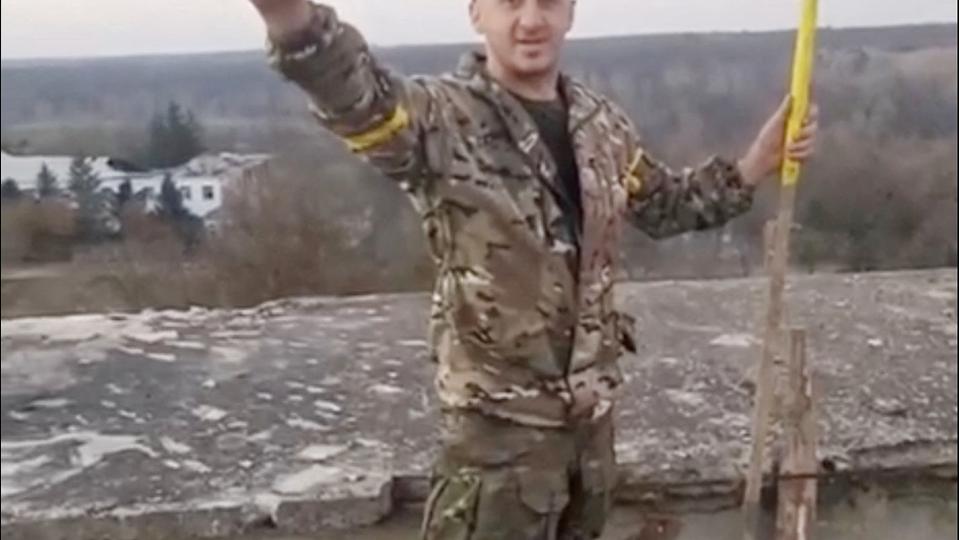 En mand i militæruniform hejser et ukrainsk flag i Kherson-regionen i det sydlige Ukraine. <i>Handout/Reuters</i>
