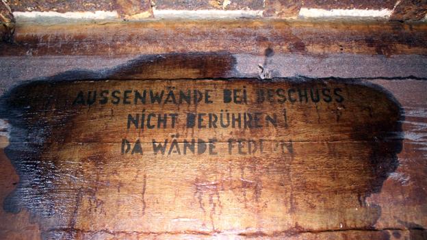 Under beskydning må ydervæggen ikke berøres, fremgår det af den skrevne tekst på en væg i en af de tyske bunkers ved broen. <i>Foto: Achim Otto</i>