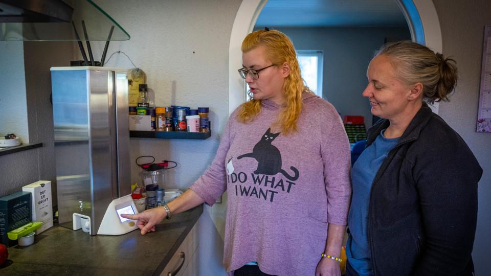 Pillerobotten står i køkkenet og meddeler, når det er tid til, at Marianne Vandrup skal tage sin medicin. Det er en god hjælp for hende. Hjemmesygeplejerske Gitte Mohr har gode erfaringer med robotten, som ti borgere i Brønderslev har i deres hjem. <i>Foto: Kim Dahl Hansen</i>