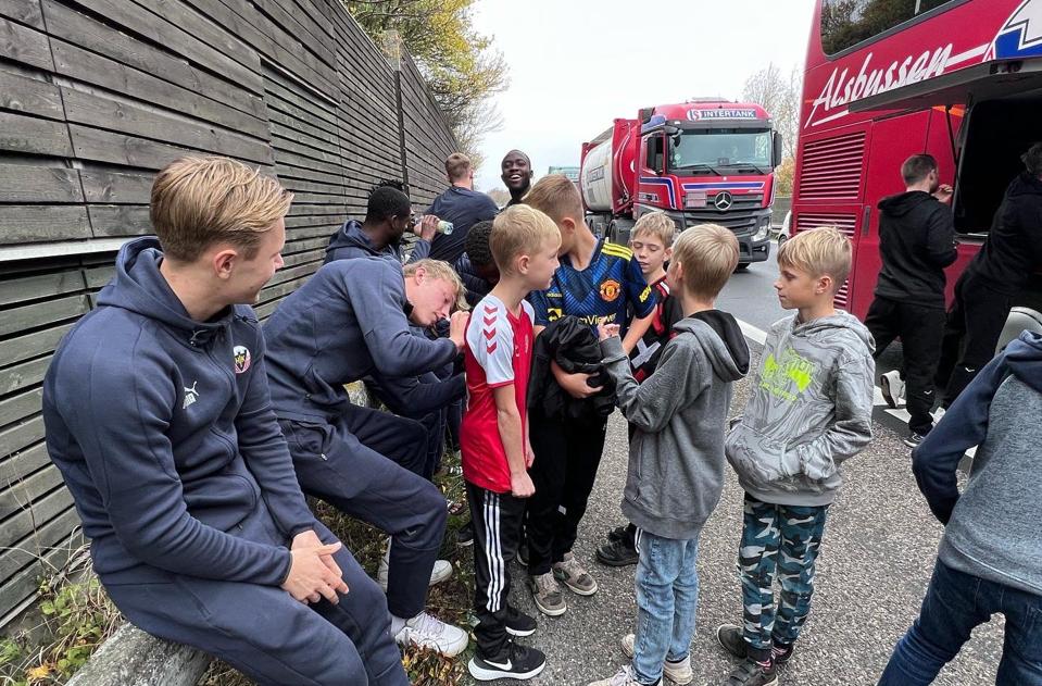 Spillerne fra Hobro IK gav autografer og selfies til børn fra en bus, der ligesom bussen fra Hobro var fanget i den lange kø inden Storebæltsbroen. <i>Foto: Hobro IK</i>